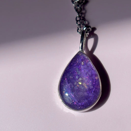 Purple cremation stone with ash in a pendant