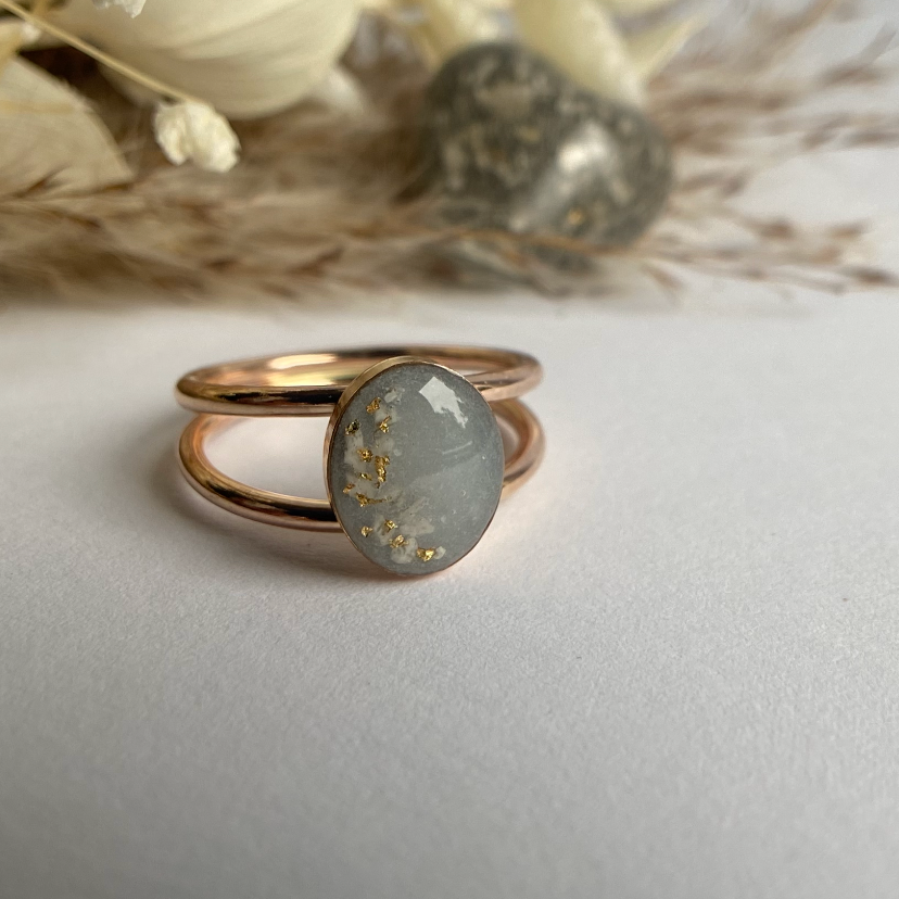 cremation ash ring with gold flakes in a gold setting with an oval double band