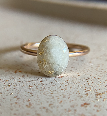 A single band gold-filled ring with a round stone on a textured background.