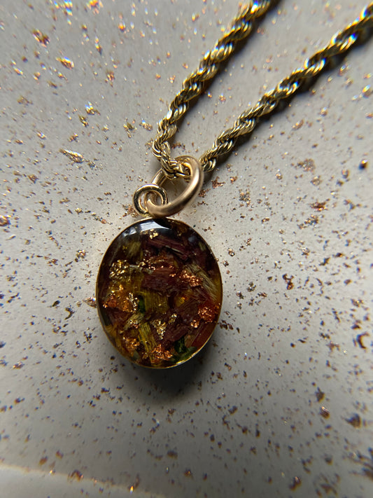 An oval pendant necklace with a gold-filled or silver setting, showcasing a multicolored stone.