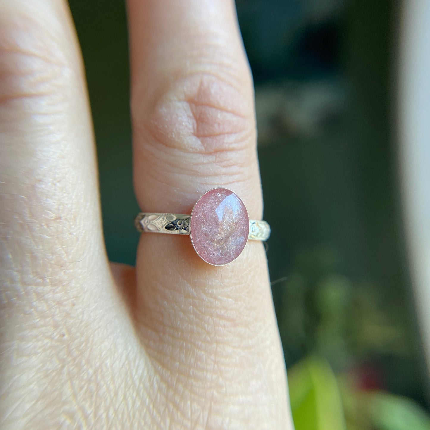 silver floral band on finger with pink ash stone